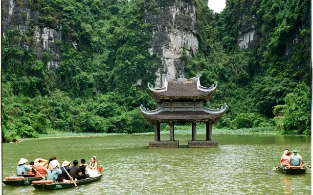 Đình nước giữa núi đá vôi và thuyền du lịch ở Tràng An, Ninh Bình